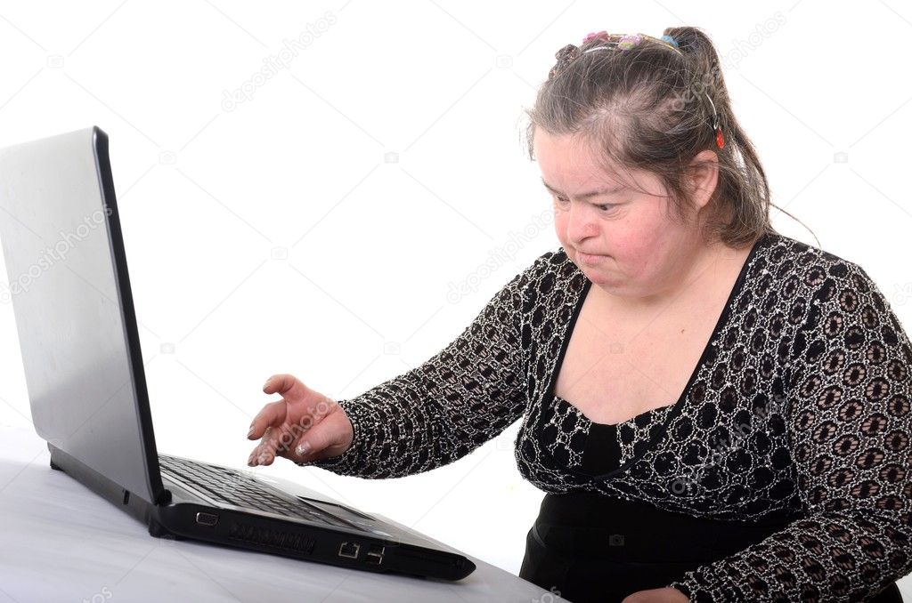 A woman with Down Syndrome sitting in front of a laptop computer.