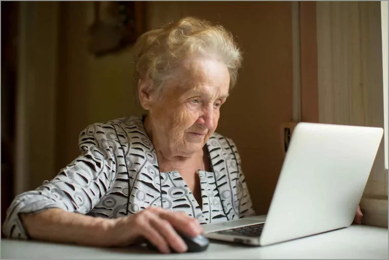 An old woman with low vision viewing a laptop screen.