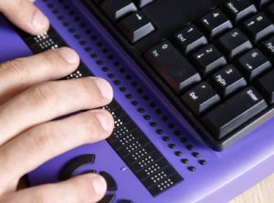 A pair of hands reading on a braille keyboard.
